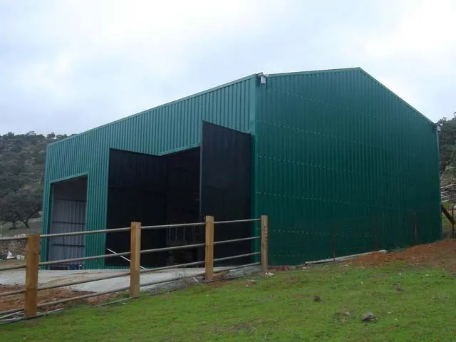 Green steel-clad agricultural building with large doors